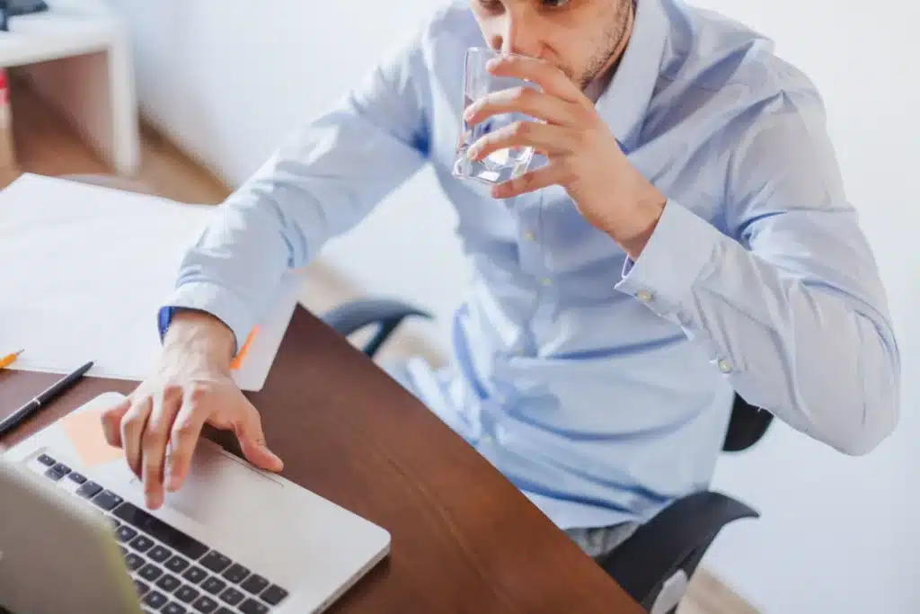 trabajador tomando agua del dispensador de agua de la oficina